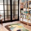 Avocado 01 rug in a wood-floored minimalist space, with thin wood bookshelves full of books and a glass-paneled space divider